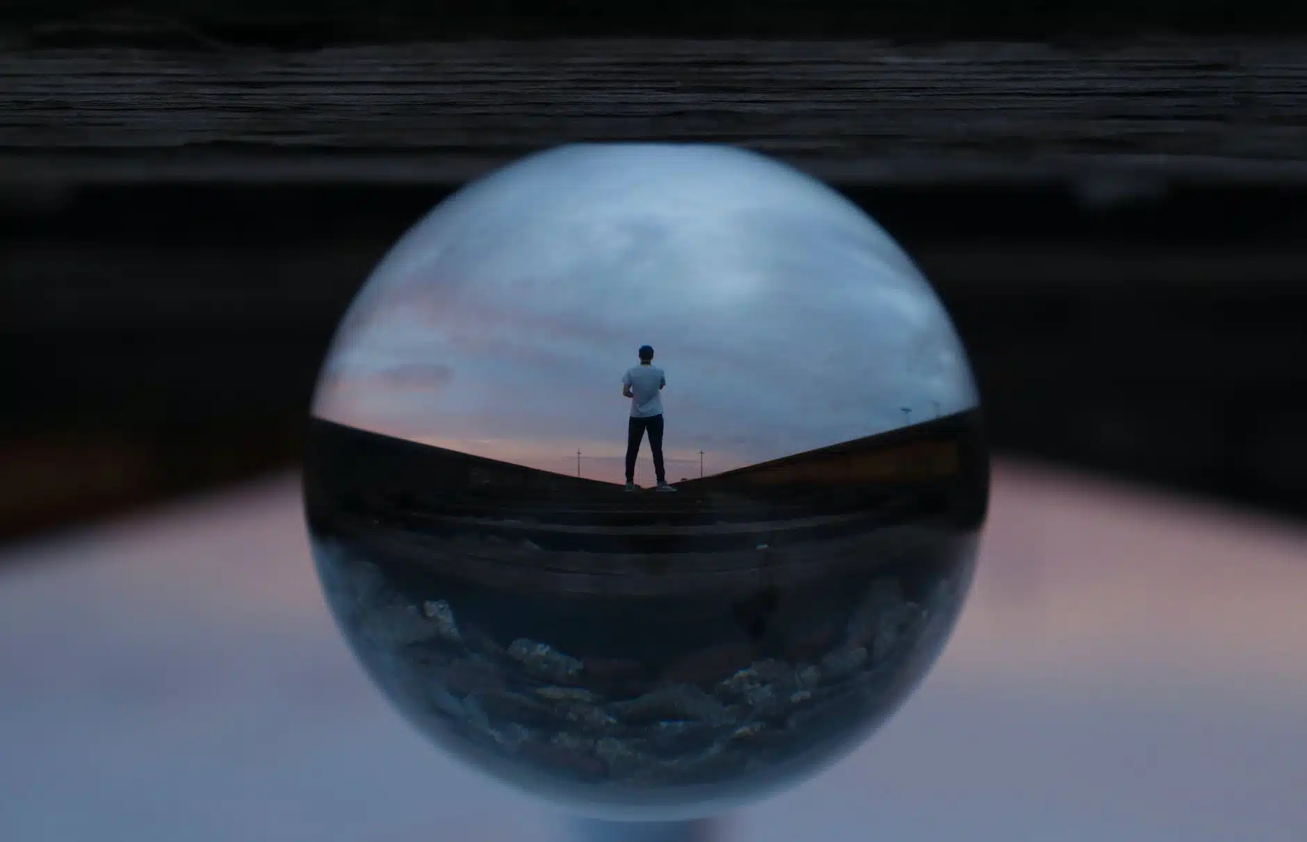 round glass ball reflecting man standing