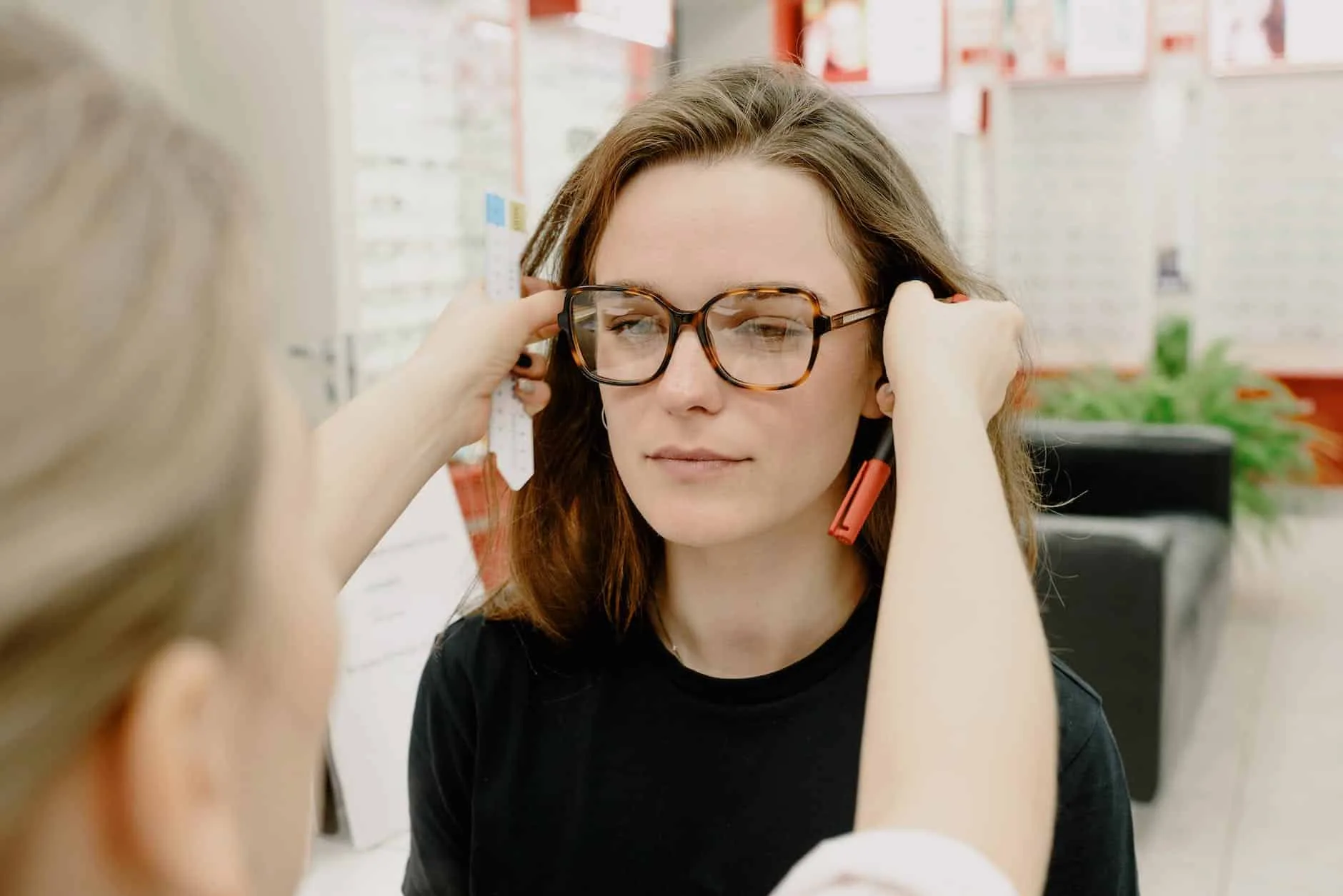 crop oculist adjusting eyeglasses on face of woman