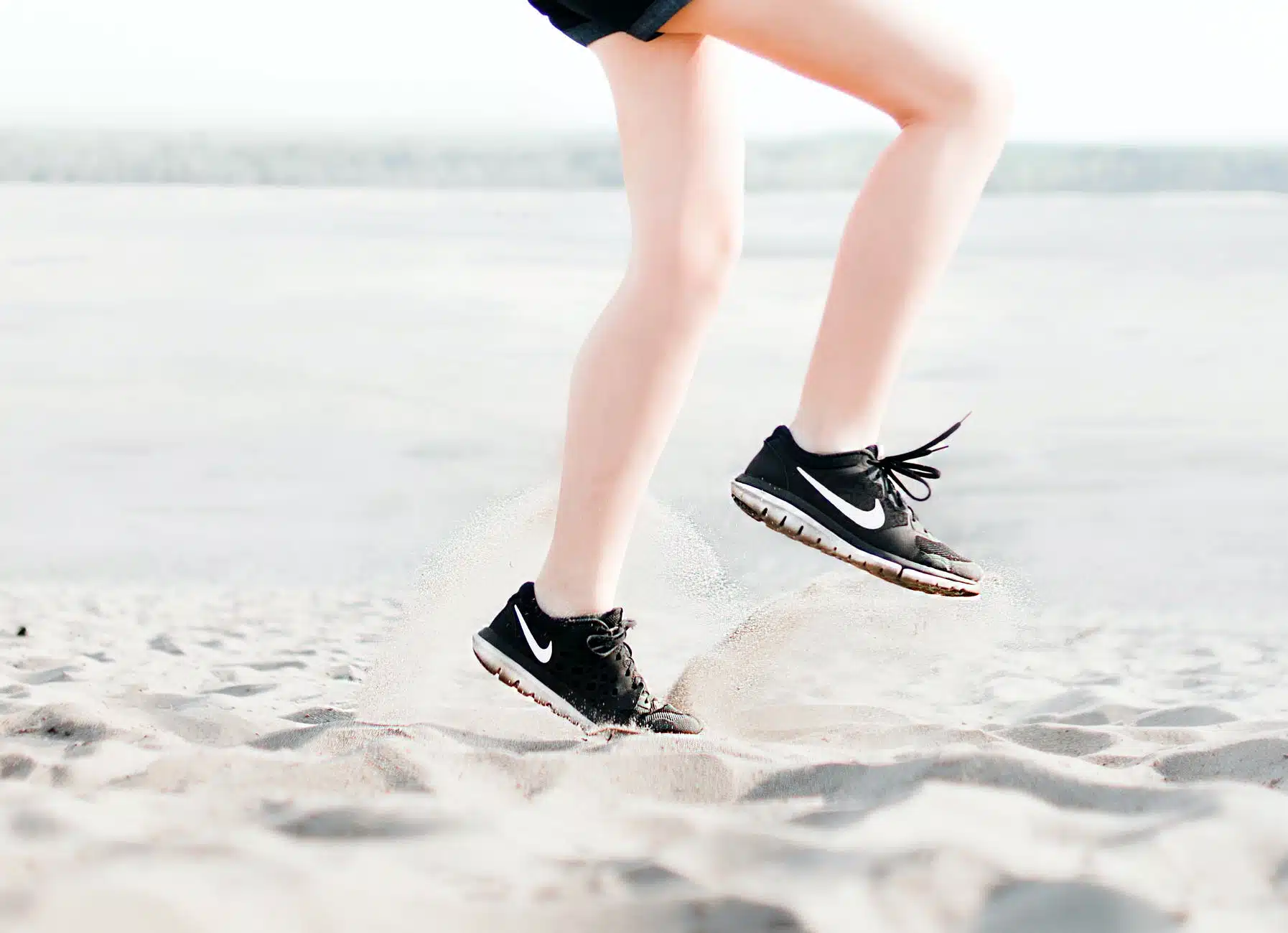 photo of woman wearing pair of black nike running shoes