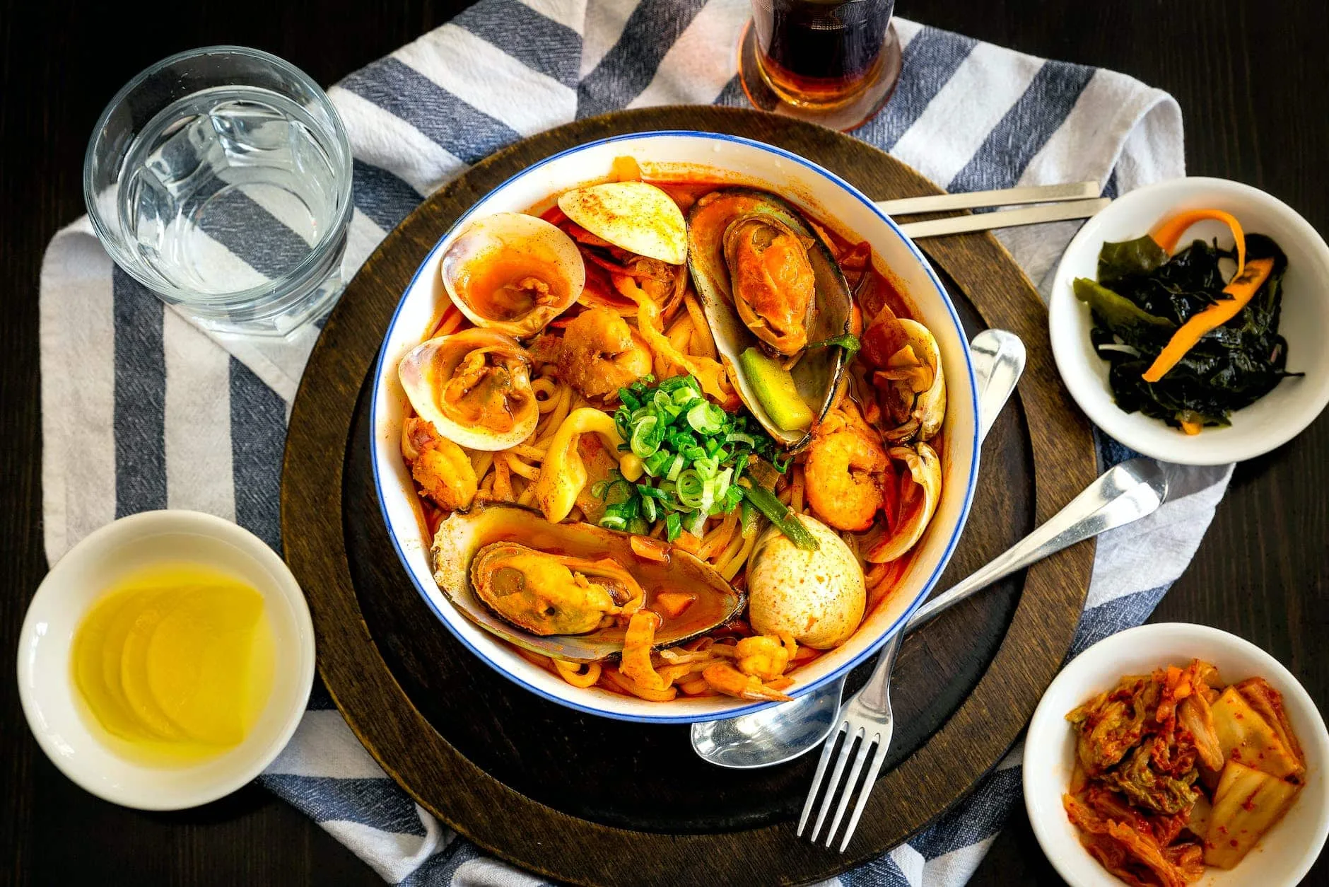 seafood delicacy on bowl near gray stainless steel fork spoon chopsticks beside water in drinking glass on table