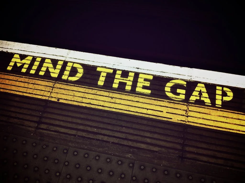 Bold 'Mind the Gap' text on a subway platform, emphasizing passenger safety.