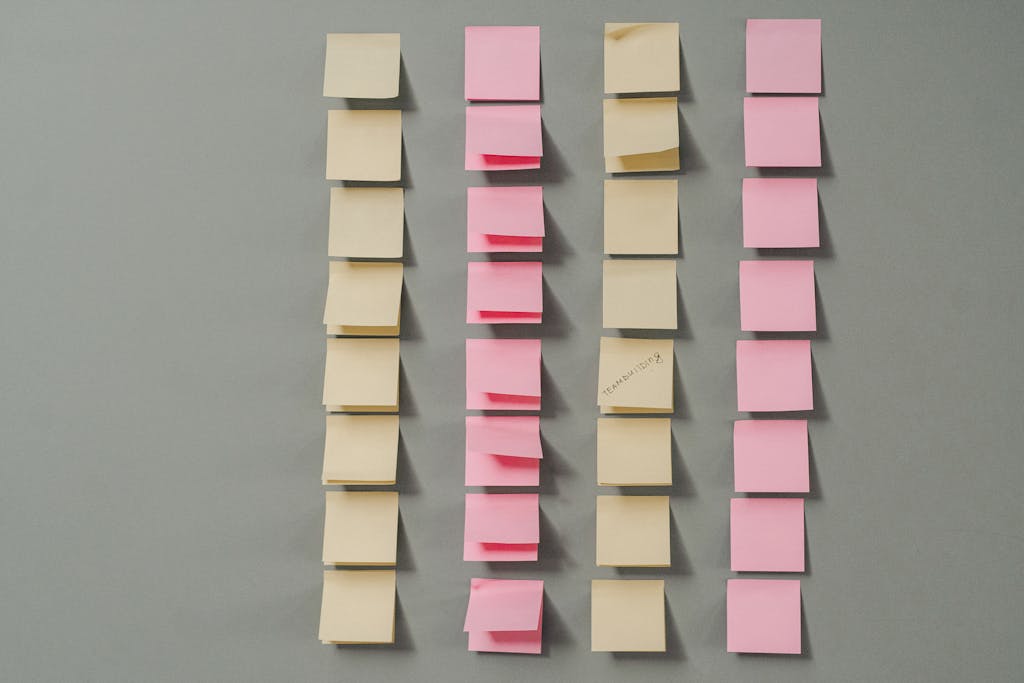 Rows of pink and yellow sticky notes on a gray background, ideal for planning concepts.